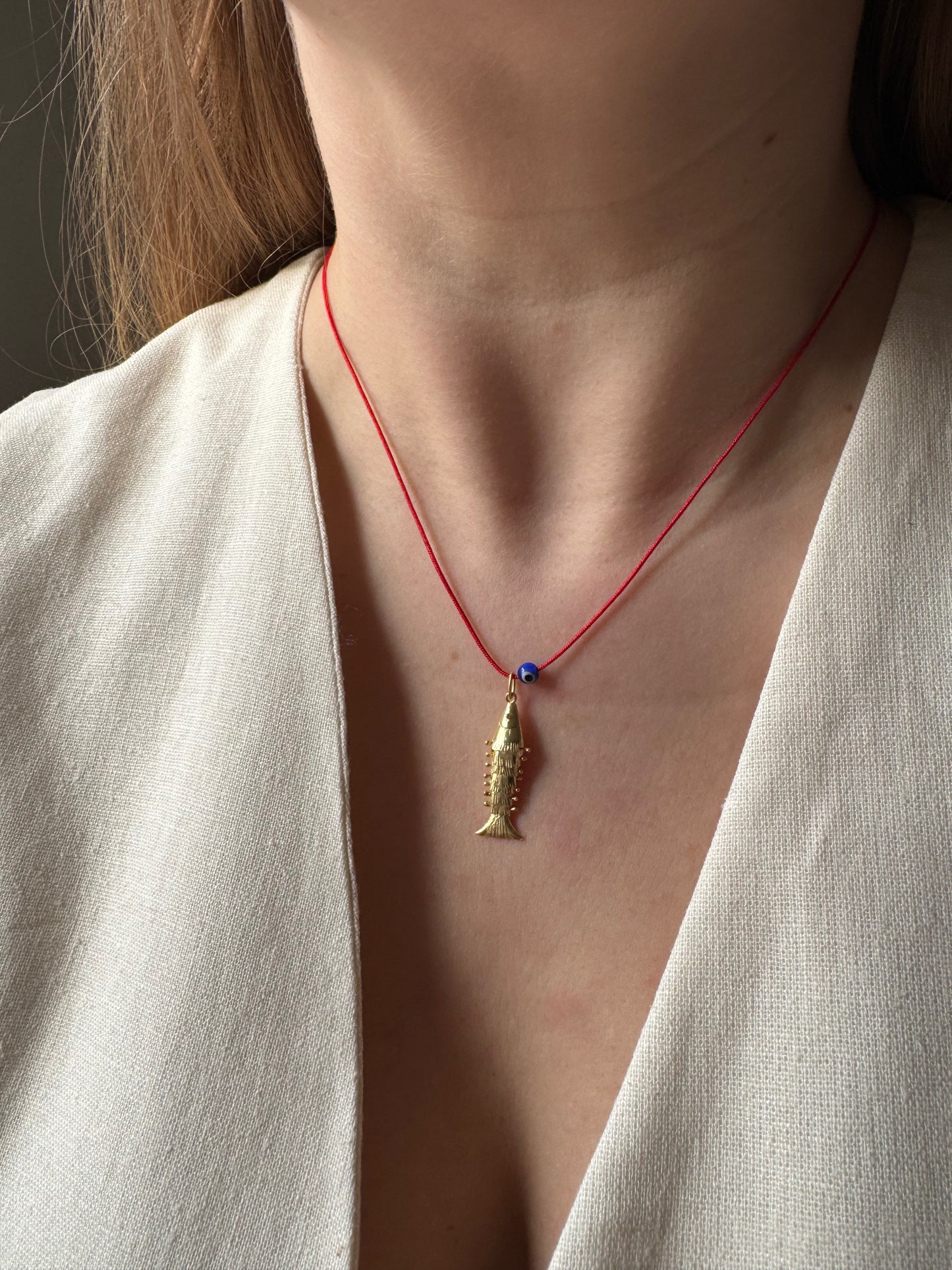 Articulated fish on a red string necklace
