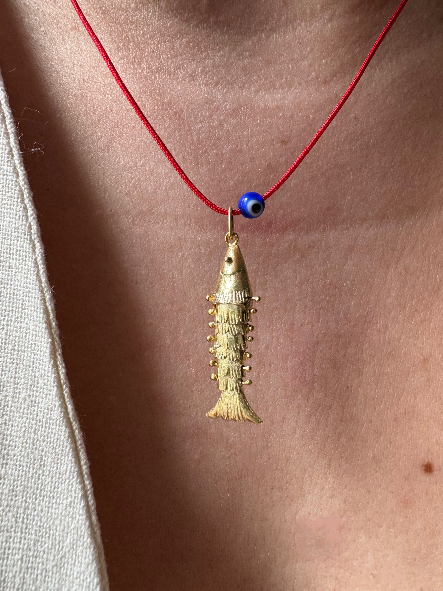 Articulated fish on a red string necklace