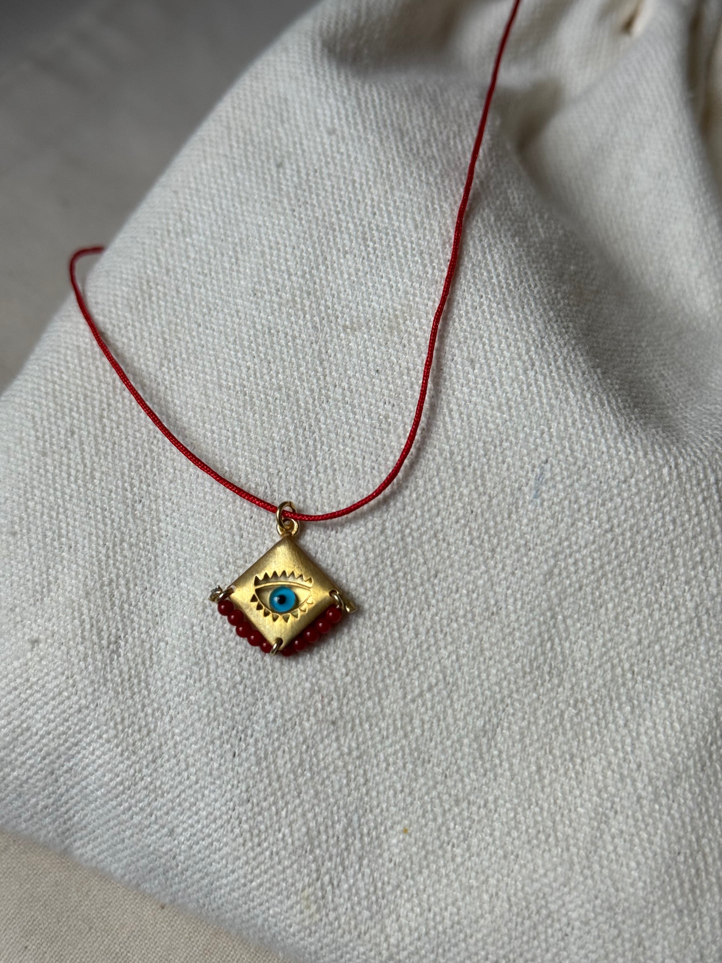 Blue eye amulet on a red string